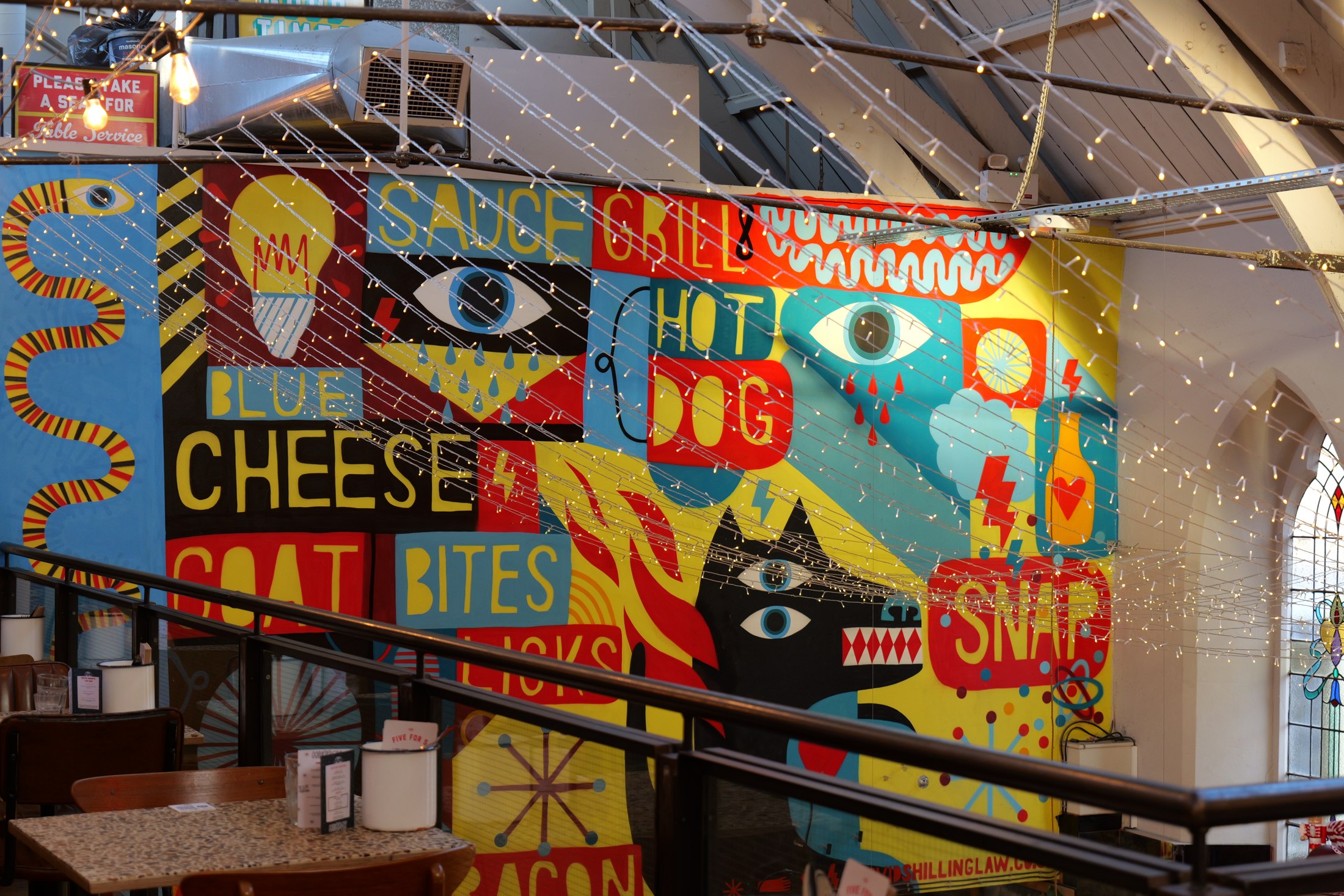 Colourful food mural and string lights inside a market hall